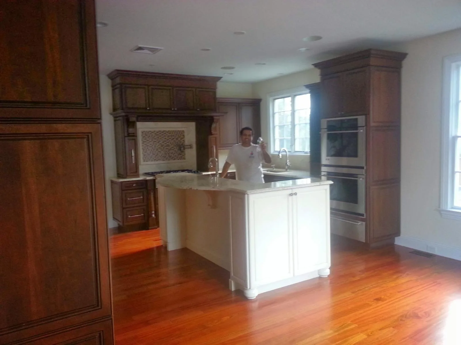 A finished kitchen with dark wood cabinetry, a white island and hardwood floors.