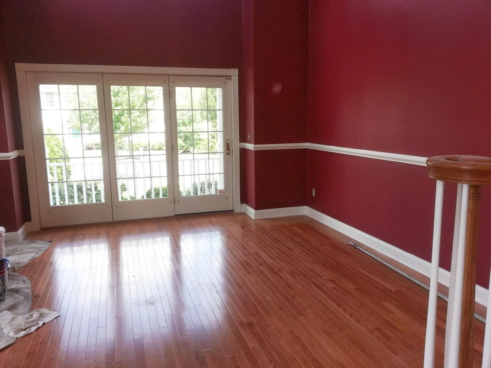 A finished room with deep red walls, white trim and a chair rail above hardwood floors.
